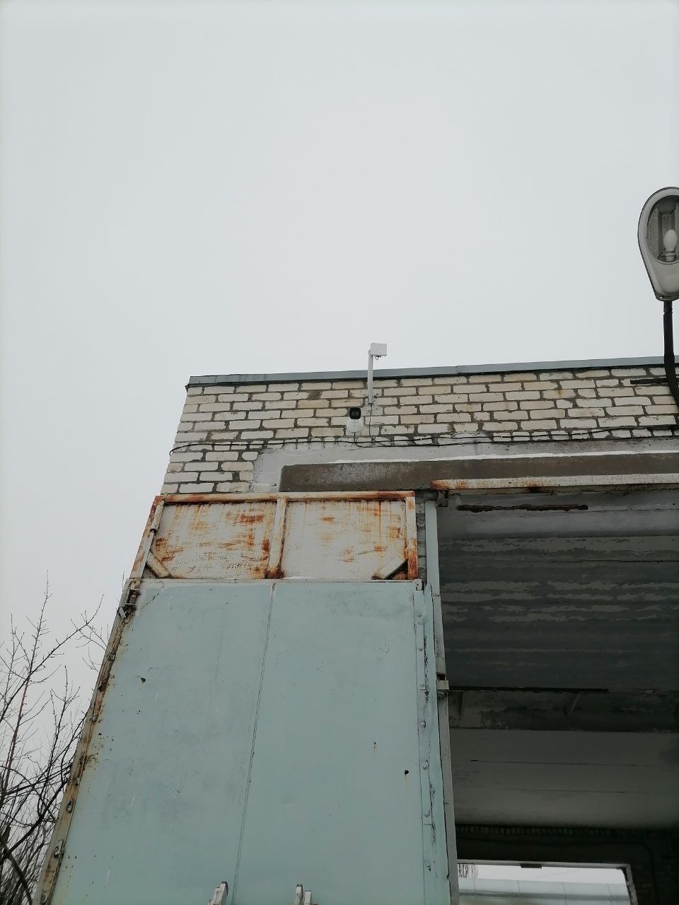 Уличная камера Dahua на столбике под крышей промышленного здания в Волгограде
